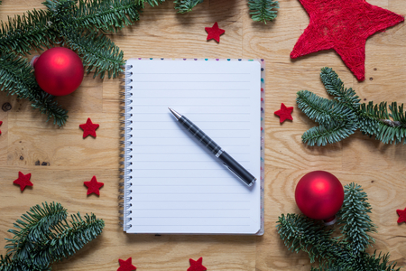 Empty notepad with Christmas decorations and fir branches on a wooden table from aboveの写真素材