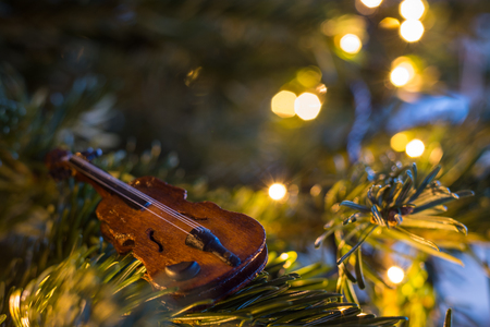 Little wooden violin ornament on a Christmas tree with fairy lights close upの写真素材