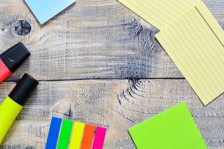 Frame of a desk with post its and a markers on a wooden backgroundの写真素材