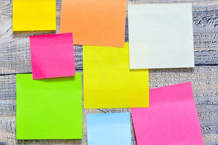 Lots of post its on wooden background with a different symbols on it