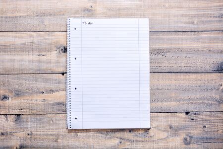 A notepad with a to do list on a wooden background