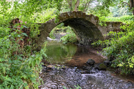 An old medieval stone bridge over a riverの写真素材