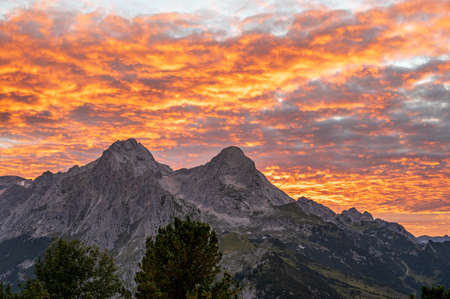 Orange clouds after sunset in the alps looks like the sky is on fire with view on mountains Alpsitze and Hochblassenの写真素材