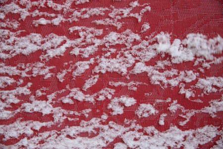 A close up of a snow covered field. The TEXTURE of the fabric is red. snow lies on red cloth. Background for wallpaperの写真素材