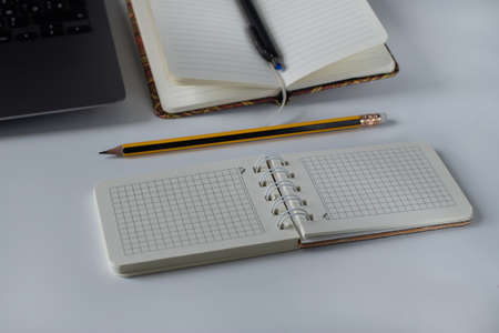 Office desk with spiral notepad, pencil and laptop on white backgroundの写真素材