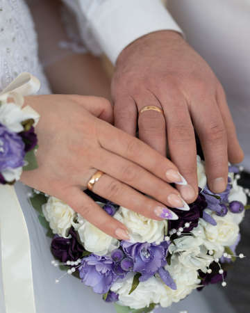 Hands of the groom and the bride on a wedding bouquetの写真素材
