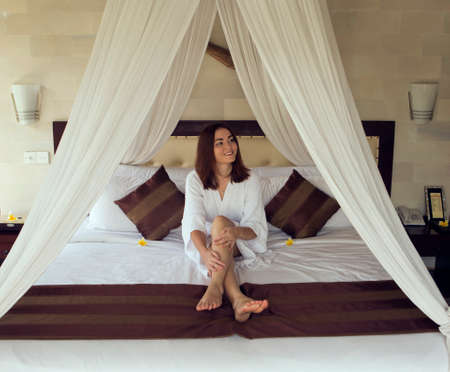 The girl smiles and irons the legs siting on a bed.の写真素材