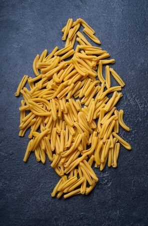 Raw italian casarecce pasta. Flatlay with raw uncooked pasta on dark background. Italian cuisineの写真素材