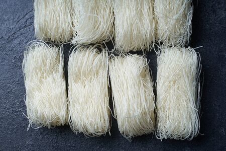 Uncooked rice noodles rolled in nests on dark background. Ingredient of asian cuisine.の写真素材