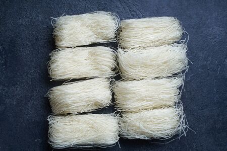  Uncooked rice noodles rolled in nests on dark background. Ingredient of asian cuisine.                             の写真素材