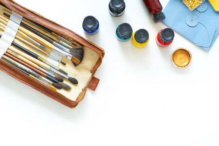 Workplace of freelance artist top view on white background. Flat lay composition with copy space. Paints, brushes and other various equipmentの写真素材