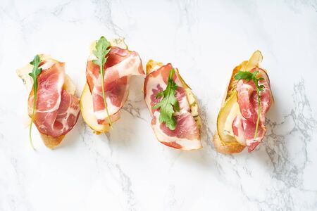 A set of bruschettas with cured meat, pear, blue cheese and ruccola. Wine appetizerの写真素材