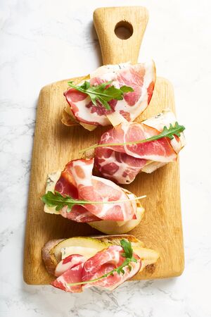 A set of bruschettas with cured meat, pear, blue cheese and ruccola. Wine appetizerの写真素材