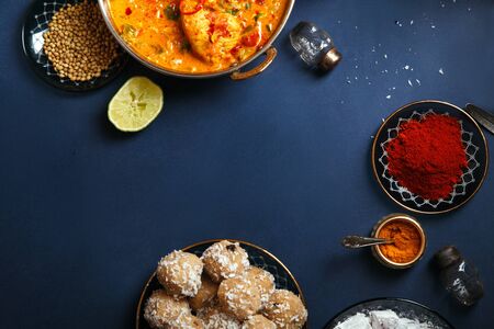 Indian cuisine on diwali holiday: tikka masala, samosa, patties and sweets with mint chutney and spices. Dark blue background with copy space centered の写真素材