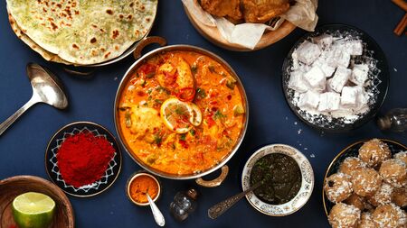 Indian cuisine on diwali holiday: tikka masala, samosa, patties and sweets with mint chutney and spices. Dark blue background. Banner compositionの写真素材