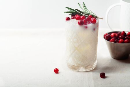 Perfect christmas cocktail: coconut margarita with cranberries and rosemary. Minimalistic concept. Linen cloth and white background. Horizontal composition with copy space.の写真素材