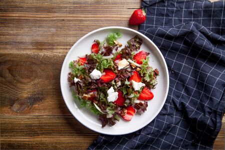 Strawberry salad with balsamic vinegar, fennel, cream cheese, walnuts and greens. Easy summer food concept. Wooden background, copy space.の写真素材