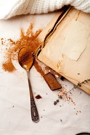 Tea spoon with spilled cocoa powder on linen background with old-fashioned cookbooks aside. Top view. Vintage kitchen concept.の写真素材