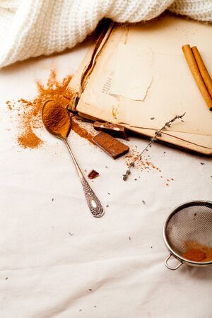 Tea spoon with spilled cocoa powder on linen background with old-fashioned cookbooks aside. Top view. Vintage kitchen concept.の写真素材