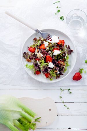 Strawberry salad with balsamic vinegar, fennel, cream cheese, walnuts and greens. Easy summer food concept. White fabric backgroundの写真素材