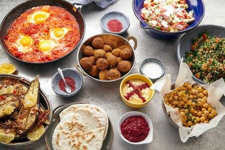Overhead image of traditional jewish and middle eastern food: falafel, fattoush, tabouli, shakshuka, balila, hummus, roasted eggplants and spicy beetroot dip. Israeli cuisine conceptの写真素材