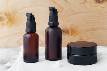 Mockup with cream jar and two brown cosmetic dispensers on linen and wooden background. Pure and minimalistic conceptの写真素材