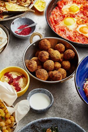 Overhead image of traditional jewish and middle eastern food: falafel, shakshuka, balila and hummus....