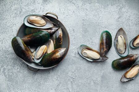 Raw kiwi mussels on textured light colored background
