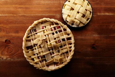 Pie crust design ideas - various ways of pie decoration with lattice and leaves. Apple, strawberry and raspberry pies uncooked on red wooden background. の写真素材