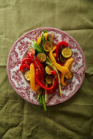 Roasted vegetables red and yellow peppers with onion and zucchini on a plateの写真素材