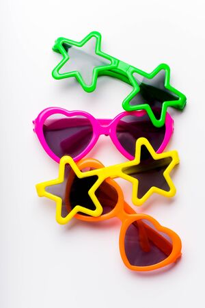 Vertical children's sunglasses in bright colors and various forms on white background. Kid's party conceptの写真素材