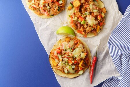 Overhead image of mexican tacos with chili con carne, sweet potatoes and grated cheese served over a...