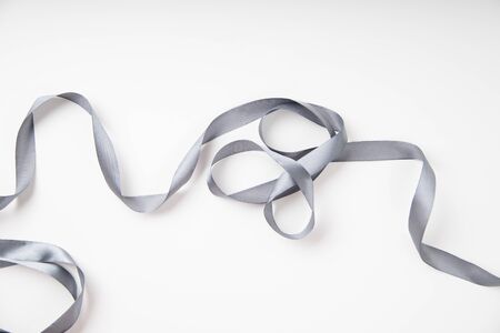Curled gray silk ribbon on white background 