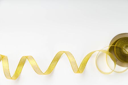 Shiny golden ribbon winded in spiral pattern on white background. Backdrop for text or announcementの写真素材