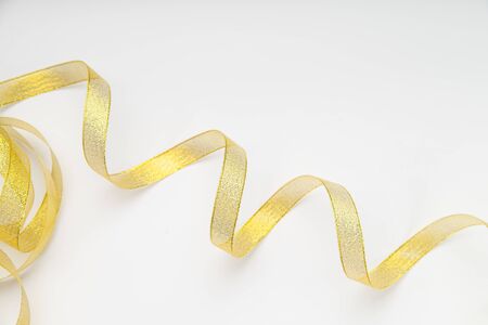 Shiny golden ribbon winded in spiral pattern on white background. Backdrop for text or announcementの写真素材