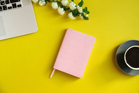 Flat lay with laptop and coffee cup on bright olive yellow background with copy spaceの写真素材