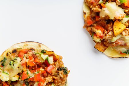Close up of mexican tacos with chili con carne, grilled sweet potatoes and grated cheese on white...