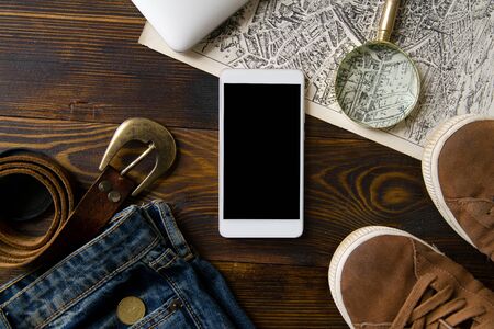 Flatlay with laptop and travel accessories: map, camera, jeans and magnifier on old wintage wooden tableの写真素材