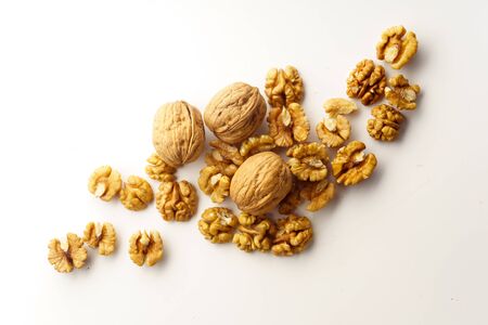 Top view of a heap of raw walnuts with a nutshell on white background isolated with copy space