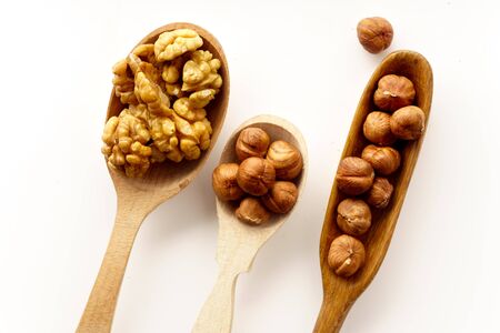 Walnuts and hazelnuts in wooden spoons isolated on white background. Top view