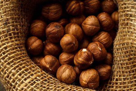 Close up image of a handful of raw hazelnuts in textile bag. Baking ingredient concept 