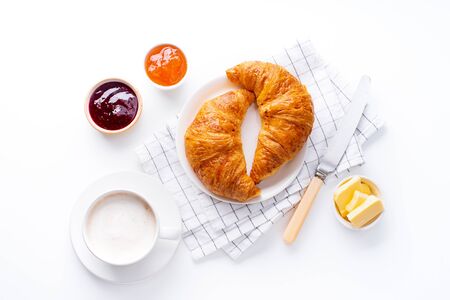 Top view flatlay with fresh croissants served with jams, coffee and buter. Morning meal concept. White backgroundの写真素材