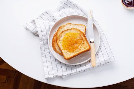 Morning toasts with butter and confiture on white table