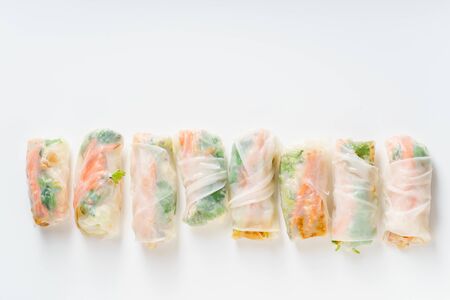Vegetarian spring rolls with tofu, marinated carrot and daikon and cilantro on white background with...