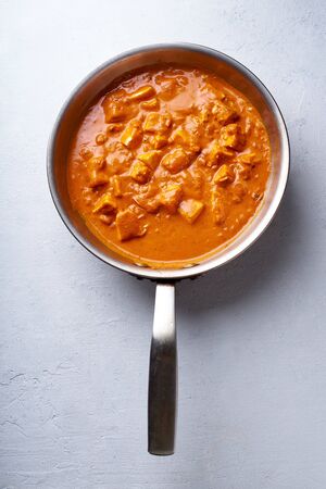 Paneer tikka masala in steel pan on concrete background. Indian cuisine, vegetarian dish made of soft cheese cubes cooked in spicy tomato sauce with cream. Top view.の写真素材