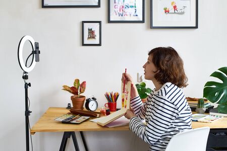 Female artist filming illustration workshop for online education during quarantine. Working from...