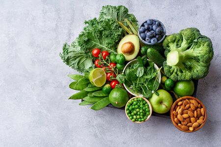 Creative flat lay with healthy vegetarian meal ingredients. Raw food concept. A variety of organic fruits, nuts, berries and vegetables in wooden box on concrete backgroundの写真素材