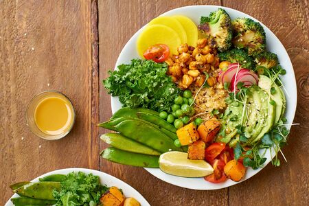 Healthy vegetarian lunch bowl with avocado, chickpeas, quinoa and vegetables, garnished with...