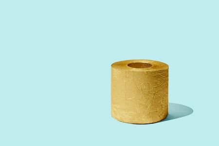Creative still life with golden toilet paper on blue background, copy spaceの写真素材