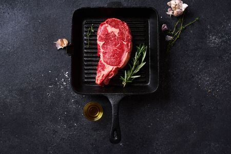 Top view Black Angus prime beef rib eye steak on cast iron grill pan with fresh rosemary and spices. Creative layoutの写真素材